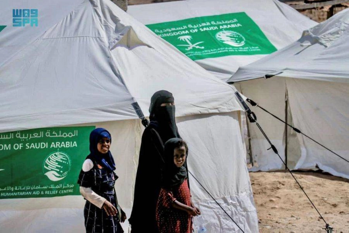 يمنية تسير مع اطفالها أمام الخيام التي نصبها المركز