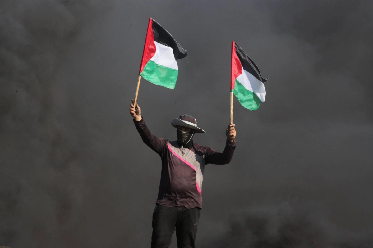 فلسطيني يرفع علم بلاده