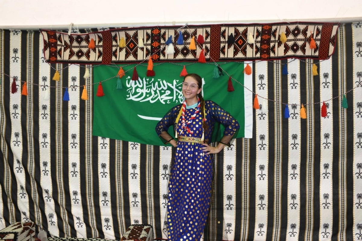 صورة تذكارية لزائرة اجنبية بجوار علم المملكة