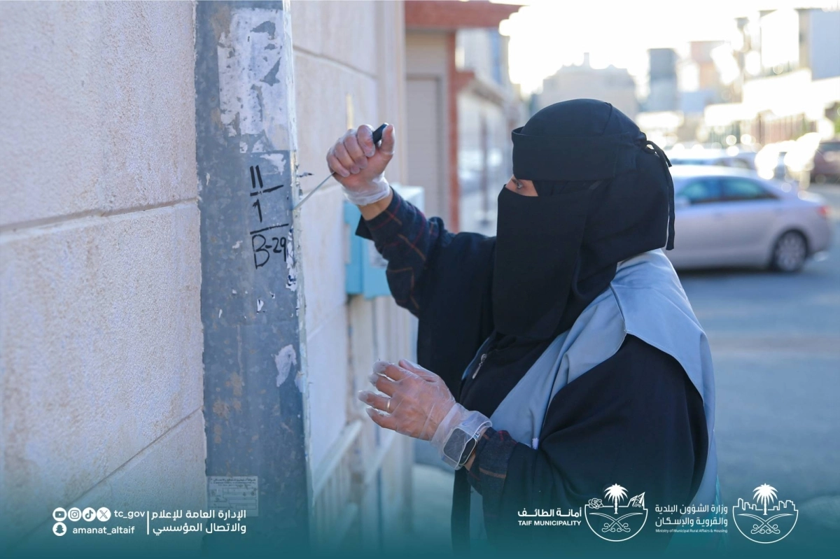 متطوعة تقوم بازالة اللصقات على الاعمدة