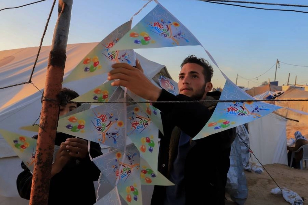 غزاوي يثبت الزينة بجوار الخيام