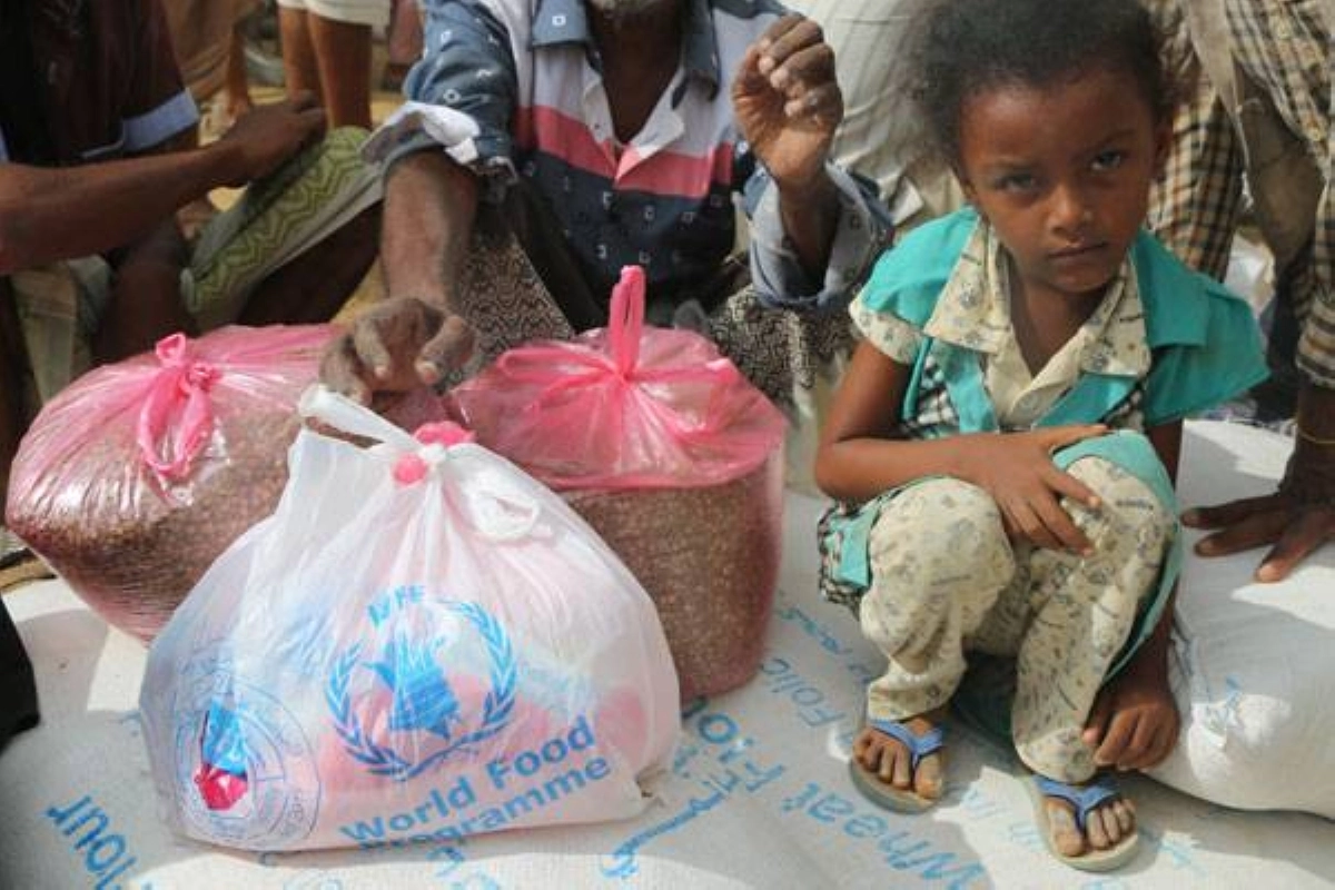 طفلة تجلس بجوار أكياس من الأمم المتحدة