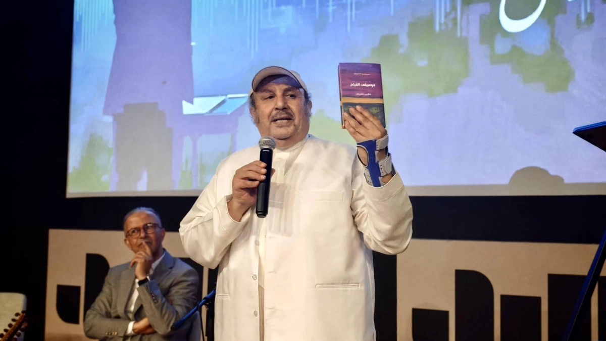 الدكتور فهد اليحيا، استشاري الطب النفسي والناقد السينمائي، يمسك بكتاب "موسيقى الفيلم: مقدمة قصيرة جداً" لكاثرين كاليناك.