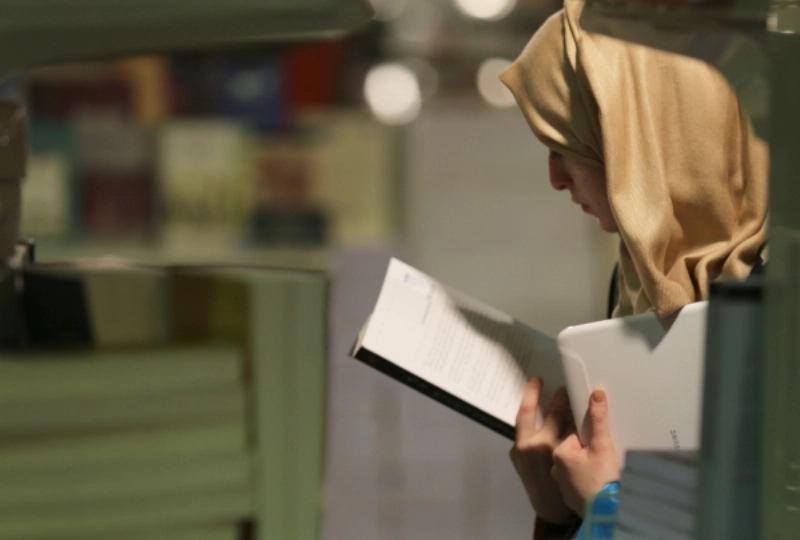 زائرة تقرأ غلاف كتاب (عمر أبوسيف)