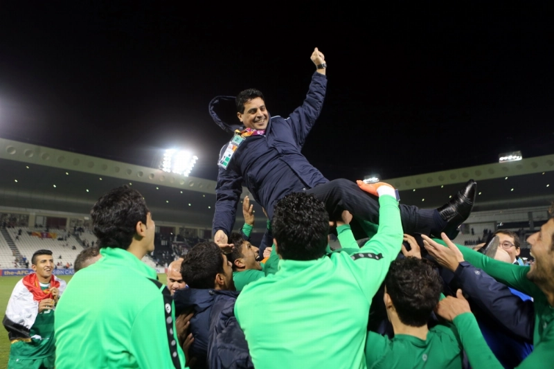 لاعبو أولمبي العراق يحتفلون مع مدربهم بالتأهل (أ ف ب)