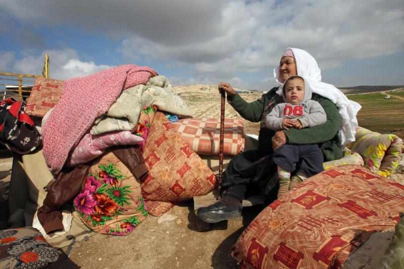 فلسطينية فوق أغراض منزلها بعد هدمه من قبل الاحتلال بالخليل (أ ف ب)
