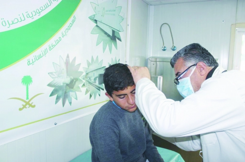 طبيب يفحص طفلا بالعيادات السعودية بالزعتري (واس)