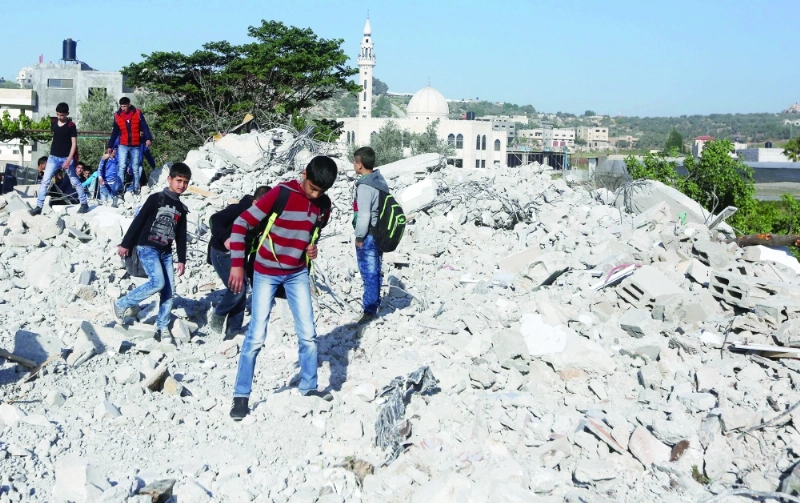 فلسطينيون على أنقاض منزل دمرته قوات الاحتلال في قباطية (أ ف ب)