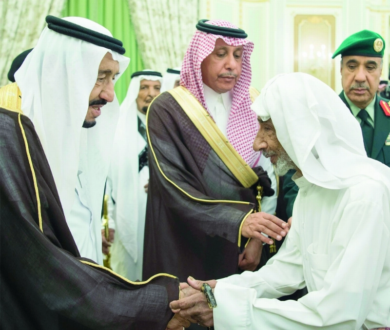 الملك سلمان مصافحا أحد المسنين لدى استقباله وزير العمل وممثلي المهن والعاملين بالقطاع الخاص في قصر اليمامة أمس (واس)