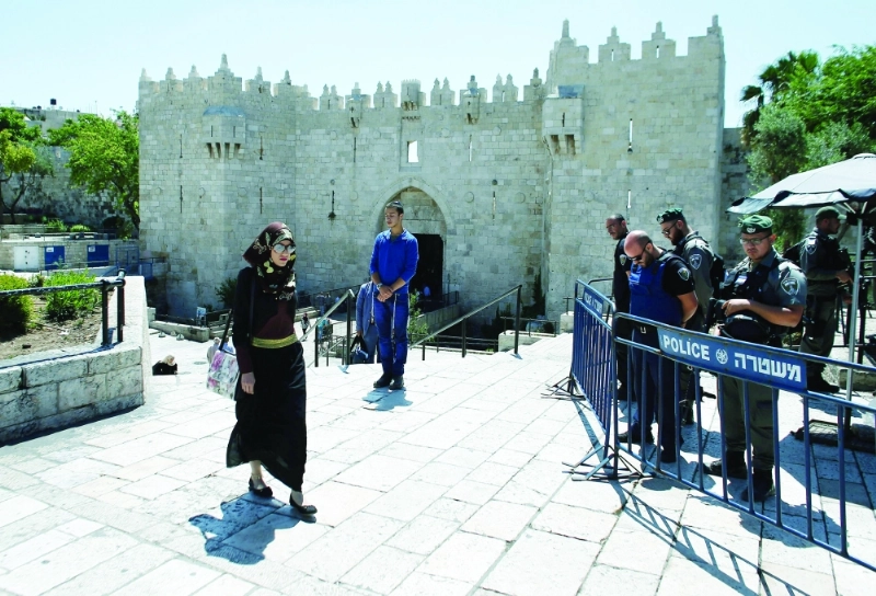 فلسطينية تمر قرب حاجز لجنود الاحتلال في القدس (أ ف ب)
