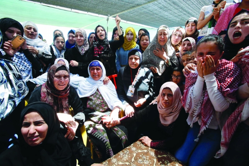 فلسطينيات خلال تشييع جثمان شاب استشهد بنيرات الاحتلال شرق الخليل (أ ف ب)
