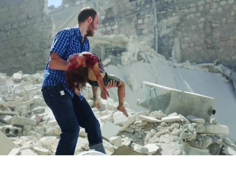 سوري يحمل جثمان طفل قتل بغارات النظام في حلب أمس (أ ف ب)