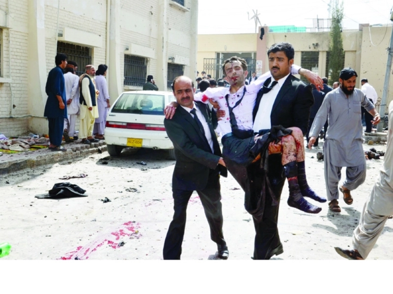 محاميان باكستانيان يحملان زميلا لهما أصيب في التفجير (إ ب أ)