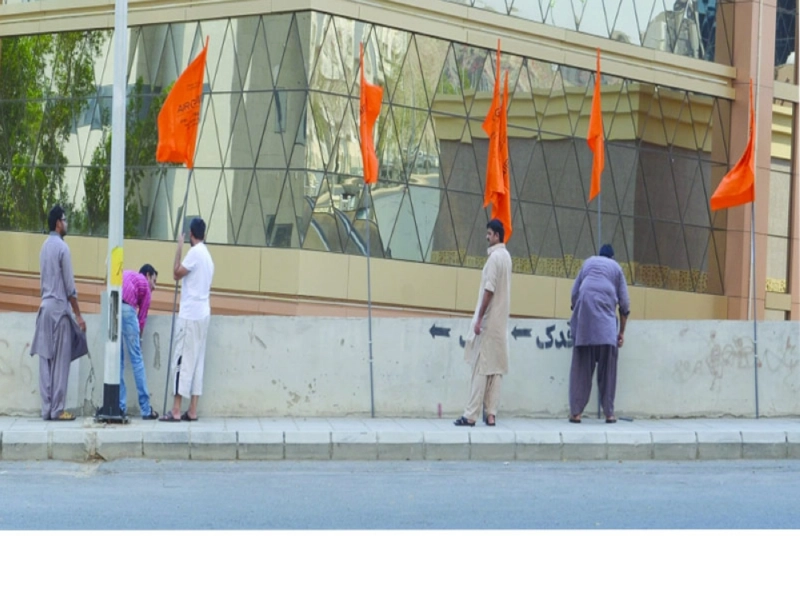 عمال يعلقون أعلاما فوق أحد الجسور أمس (عبدالمحسن دومان)