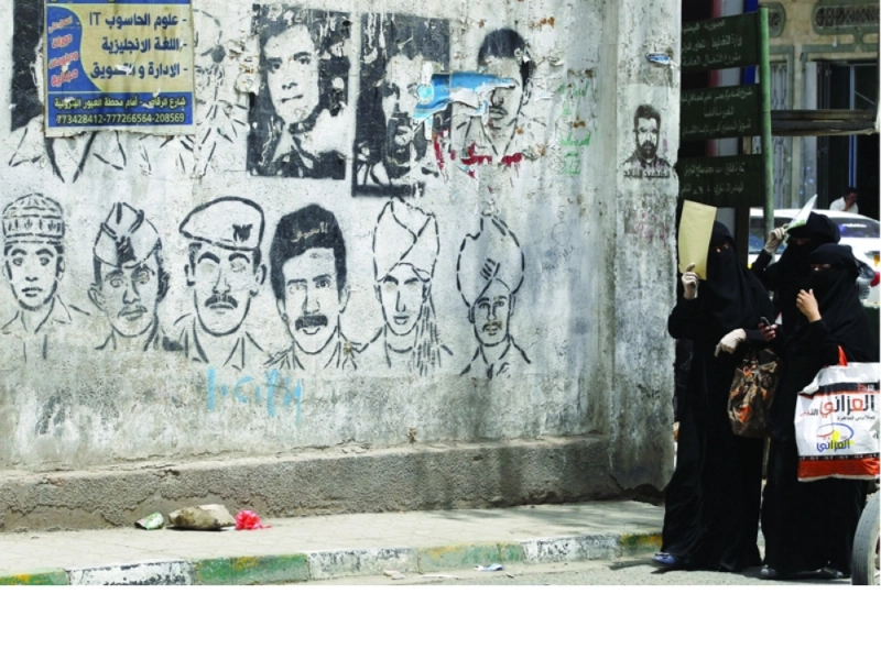 يمنيات يسرن بجوار رسم جرافيتي على جدار في صنعاء بمناسبة اليوم العالمي لضحايا الاختفاء القسري (إ ب أ)
