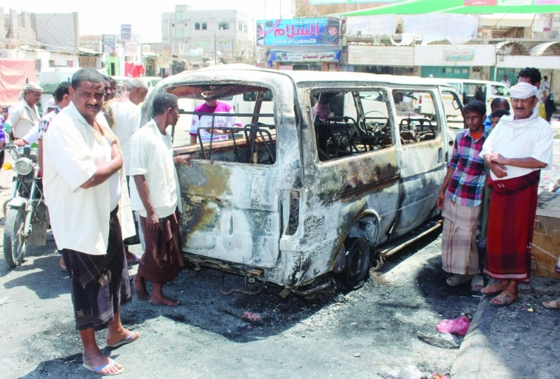يمنيون حول حافلة صغيرة تحطمت بانفجار عبوة في حوطة لحج أمس (أ ف ب)