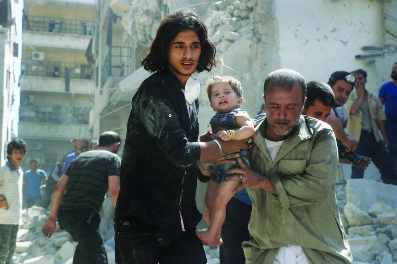 سوريون يحملون فتاة انتشلت من ركام مبنى إثر غارة في حلب (أ ف ب)
