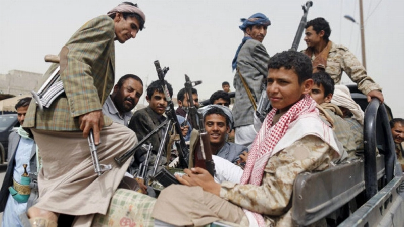 Houthi fighters ride a patrol truck outside Sanaa Airport