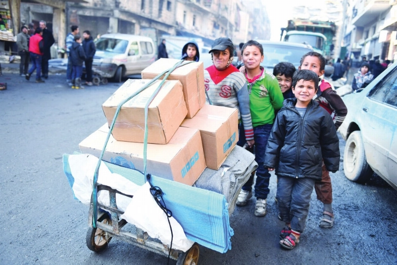 أطفال يدفعون عربة تحمل مواد إغاثة أممية شرق حلب (رويترز)