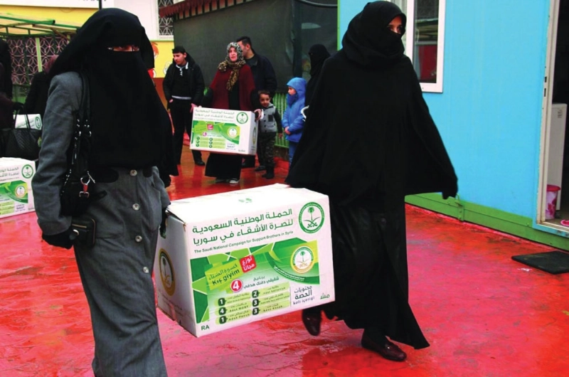 لاجئتان سوريتان تحملان مساعدات سعودية (واس)