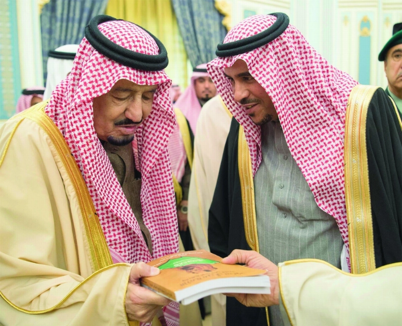 الملك سلمان مطلعا على كتاب قدمه له أحد الضيوف