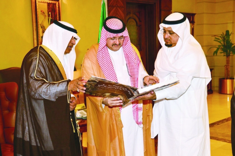 مشعل بن ماجد متسلما أحد الإصدارات من بكري عساس أمس (واس)
