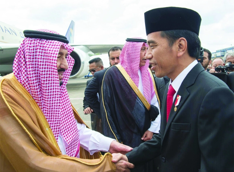 الملك سلمان مصافحا الرئيس الإندونيسي لدى وصوله مطار حليم الدولي في جاكرتا اليوم (بندر الجلعود)