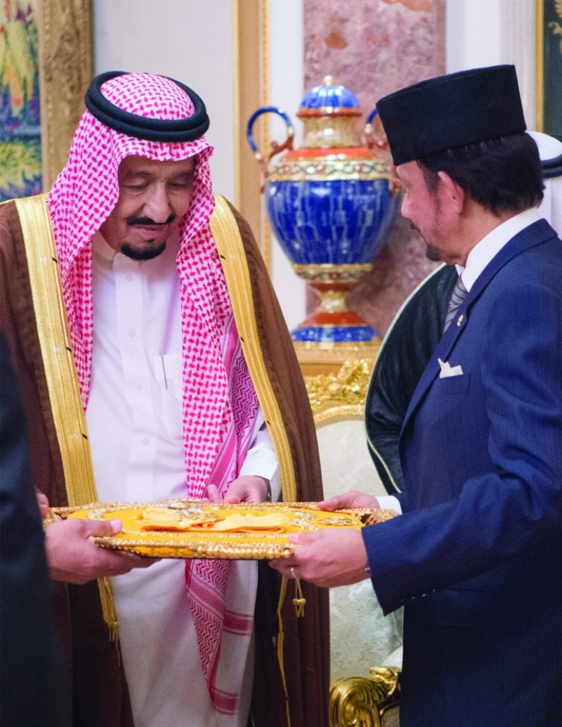 الملك سلمان متسلما وسام الأسرة المالكة للعرش البروناي من السلطان حسن البلقيه أمس (بندر الجلعود)