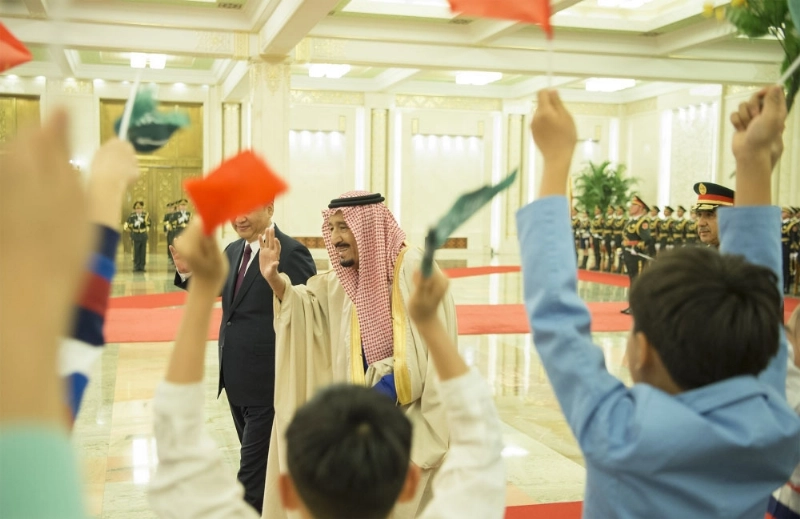 الملك سلمان محييا مجموعة من الأطفال خلال مراسم استقباله (بندر الجلعود)