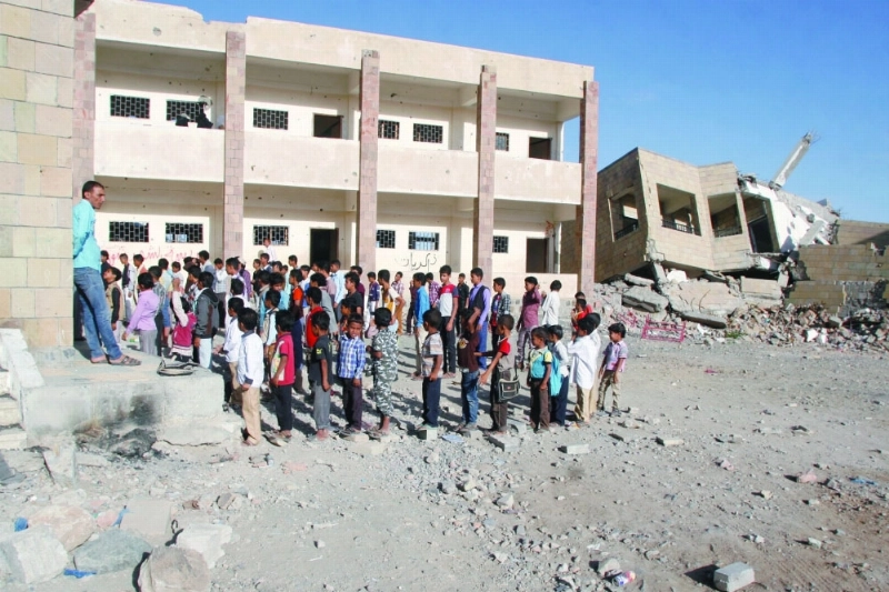 طلبة يمنيون في ساحة مدرسة بتعز دمرتها صواريخ الحوثي (رويترز)