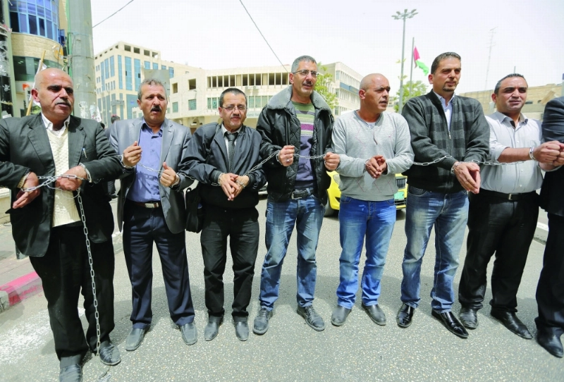 فلسطينيون يقيدون أيديهم بالسلاسل تضامنا مع الأسرى (إ ب أ)