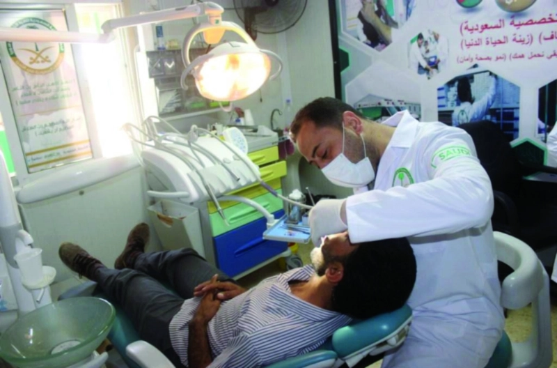طبيب أسنان يعالج لاجئا سوريا في عيادات الزعتري (واس)