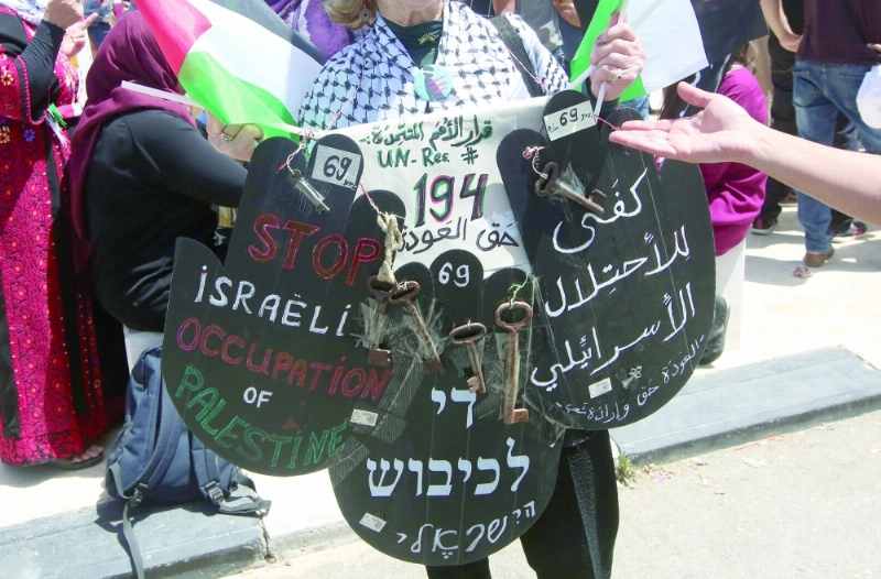 فلسطيني يحمل لافتة تندد بالاحتلال في يوم النكبة، أمس (إ ب أ)