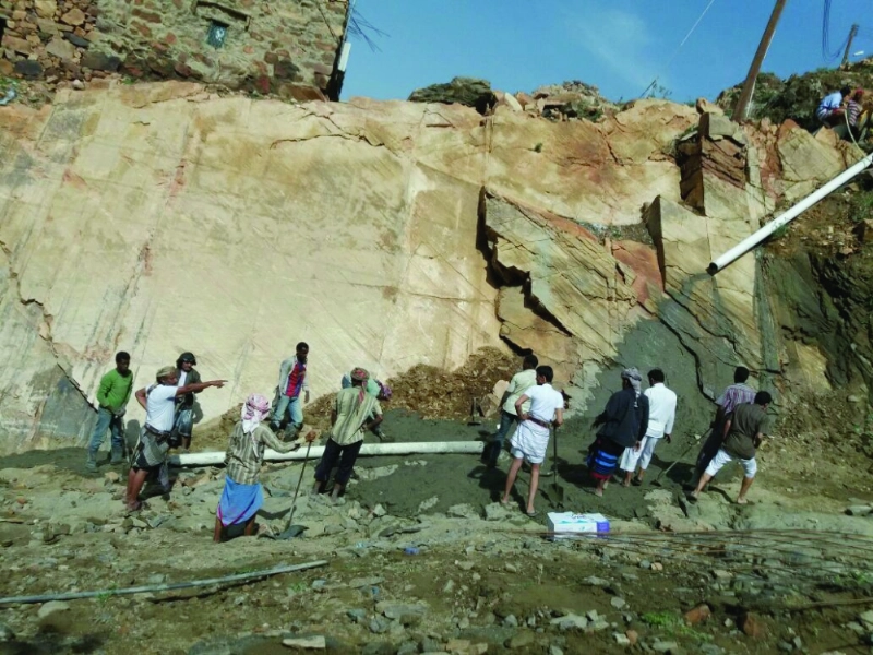 المواطنون خلال مسحهم طريق عقبة الشايف مستخدمين الاسمنت