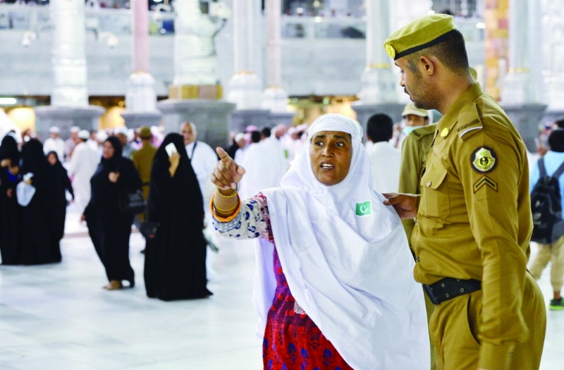 أحد أفراد القوة الخاصة يساعد معتمرة (واس)