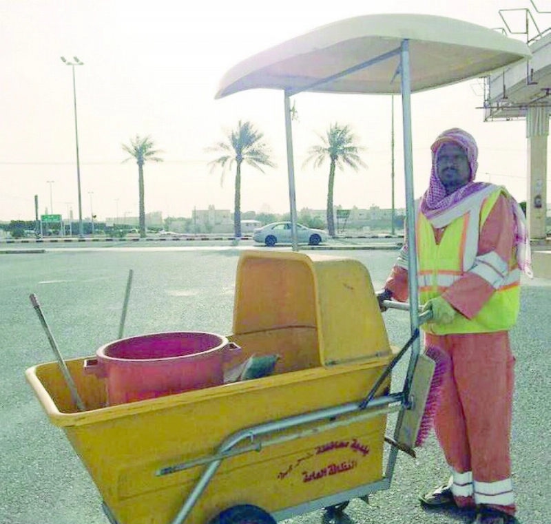 عامل نظافة يحتمي عن الشمس بمظلة (واس)