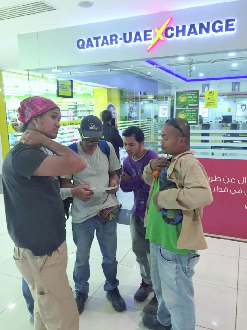 عمالة أمام أحد محال الصرافة بالدوحة (مكة)