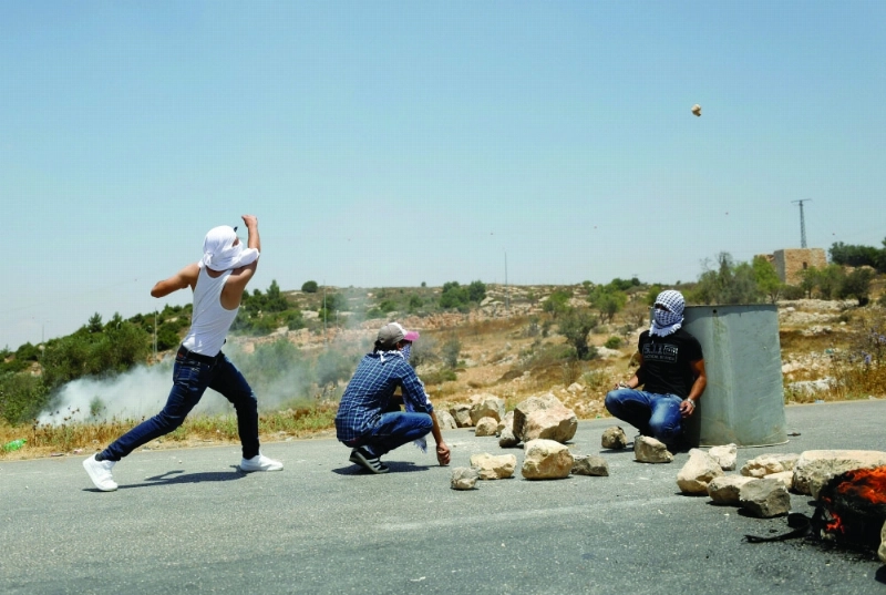 فلسطيني يلقي حجارة باتجاه قوات الاحتلال (رويترز)
