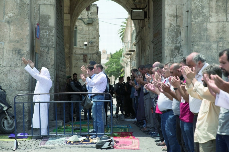فلسطينيون يصلون خارج الأقصى رفضا لإجراءات الأمن الإسرائيلية (إ ب أ)