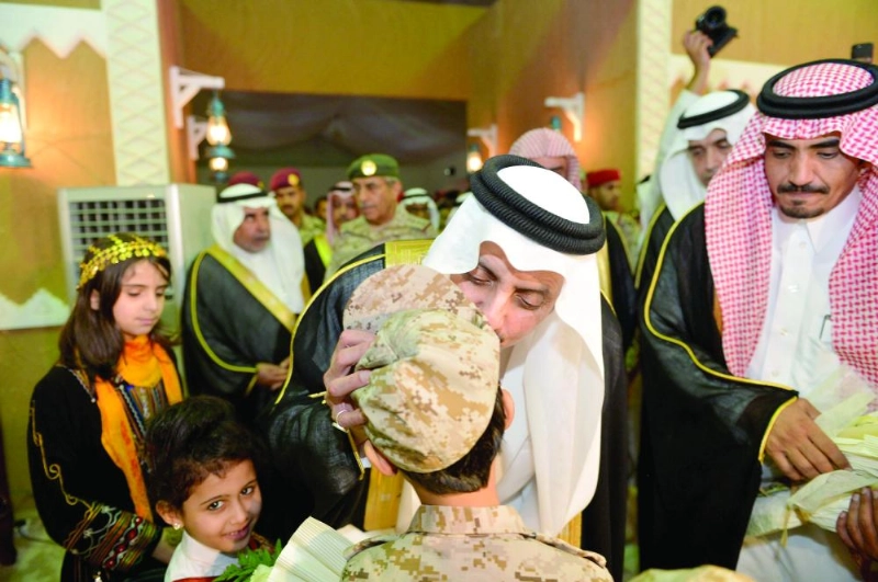 أمير عسير يقبل أحد أبناء الشهداء