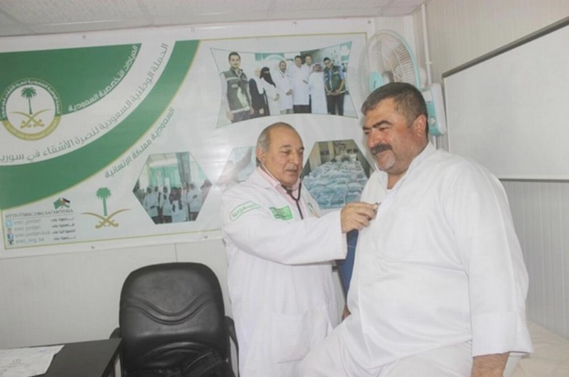 طبيب يعالج لاجئا سوريا في العيادات السعودية بالزعتري (واس)