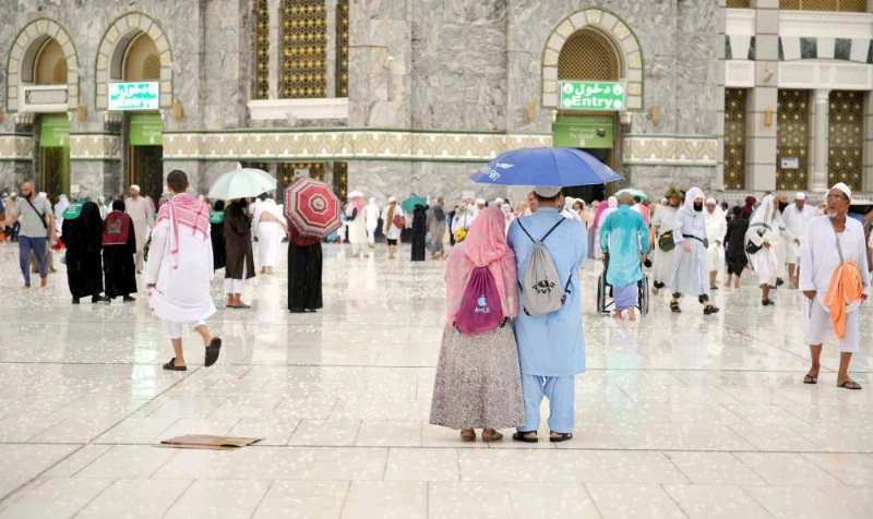 حجاج في ساحات الحرم المكي يحتمون بالمظلات من الأمطار التي هطلت أمس (واس)