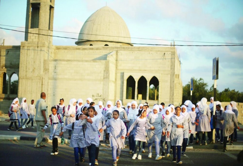 طالبات فلسطينيات في طريقهن إلى مدرسة تديرها الأمم المتحدة في مخيم دير البلح (رويترز)