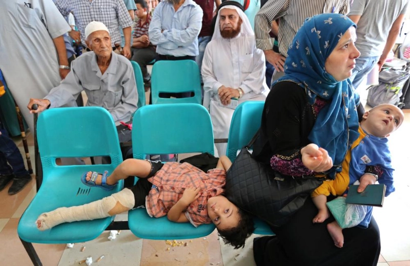 فلسطينية وأطفالها تنتظر في منفذ رفح غزة للعبور إلى مصر (د ب أ9