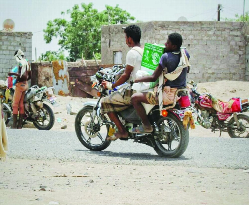 يمنيون في محافظة تعز يحملون سلالا غذائية من مركز الملك سلمان (واس)