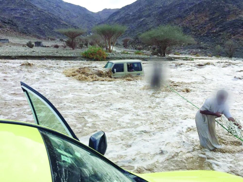 رجال الدفاع المدني خلال إنقاذ مركبة محتجزة بأحد الأودية في المدينة المنورة أمس (تويتر)