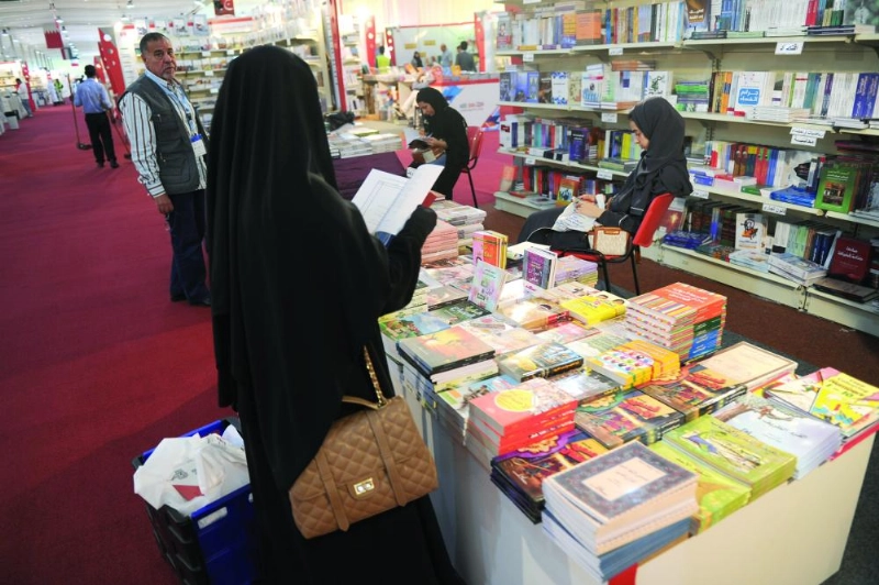 زائرة تطلع على أحد الكتب بالمعرض (مكة)