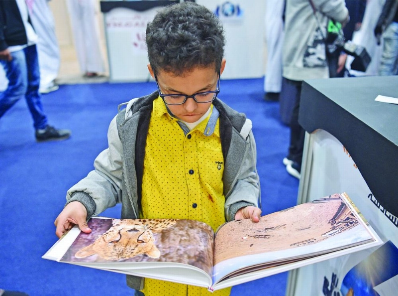 طفل يشاهد أحد الكتب عن الحياة البرية (ياسر بخش)