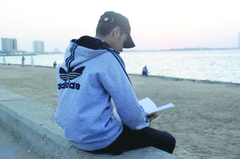 شاب يتصفح أحد إصدارات معرض الكتاب بجدة على شاطئ أبحر (مكة)