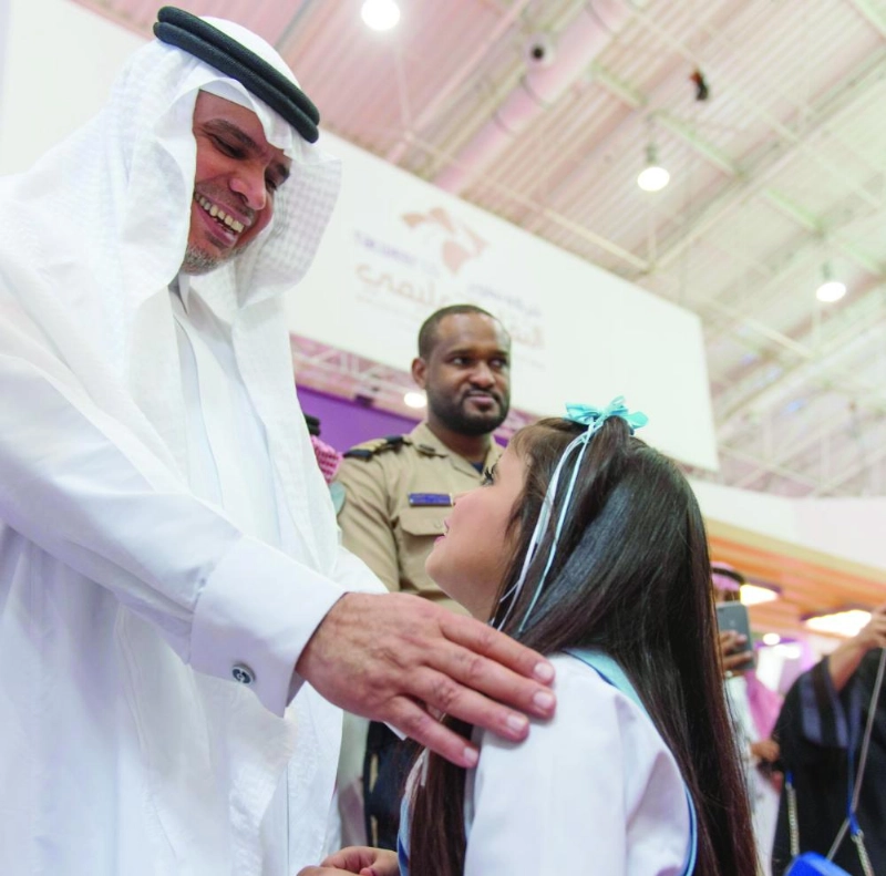 أحمد العيسى يداعب طفلة خلال افتتاح المنتدى أمس (واس)